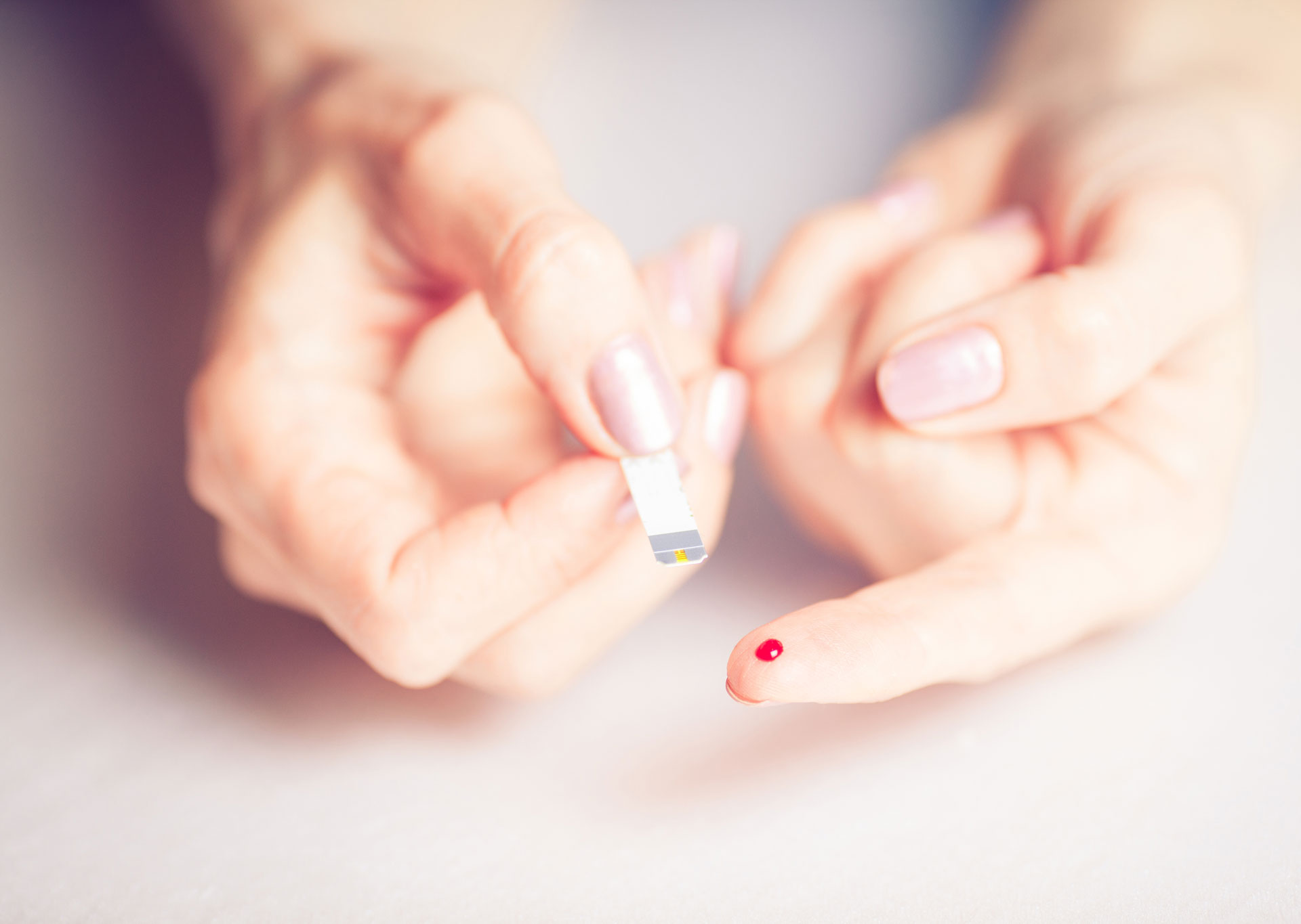 Finger mit Bluttropfen und Teststreifen