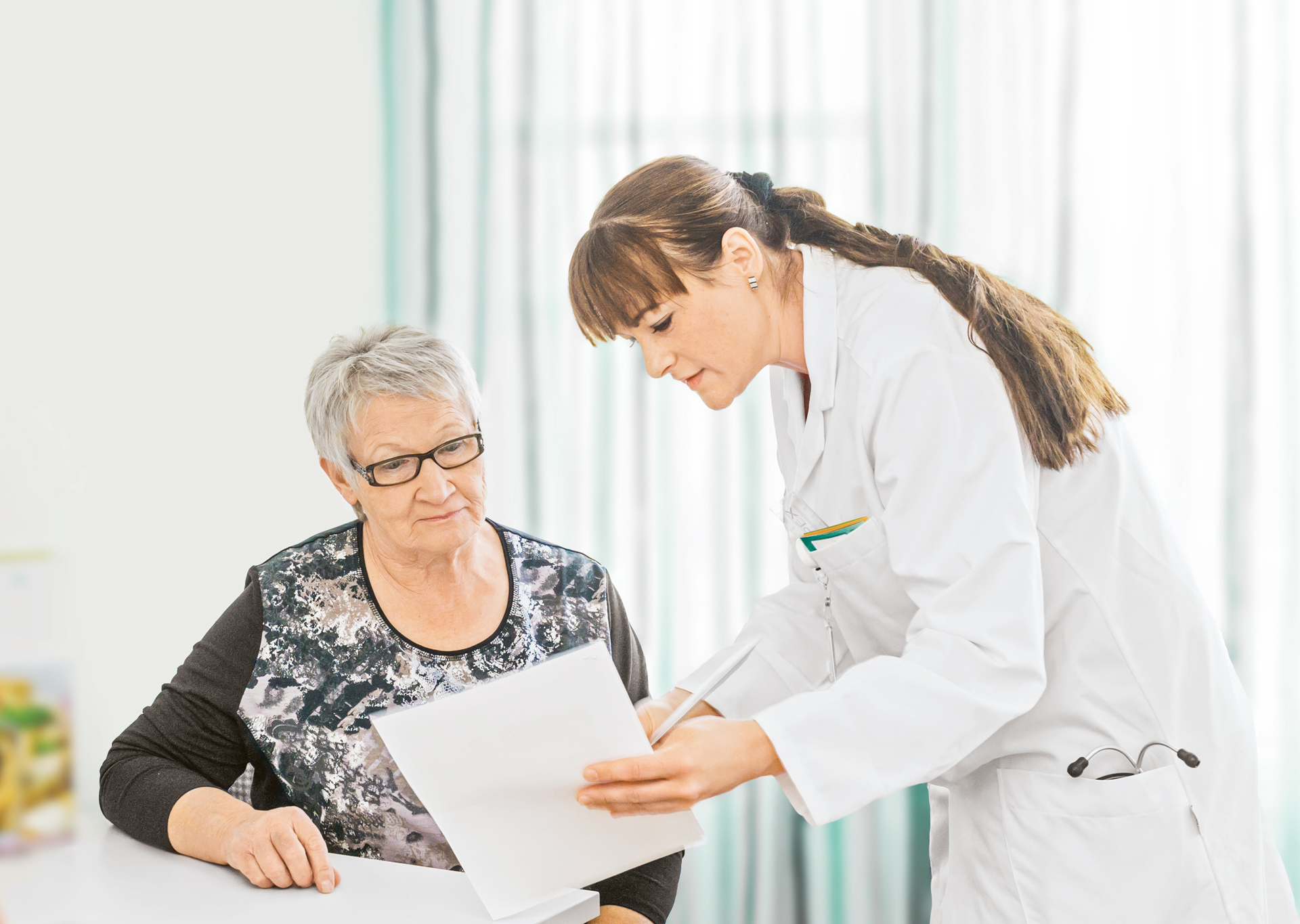 Ärztin erklärt Patientin Unterlagen
