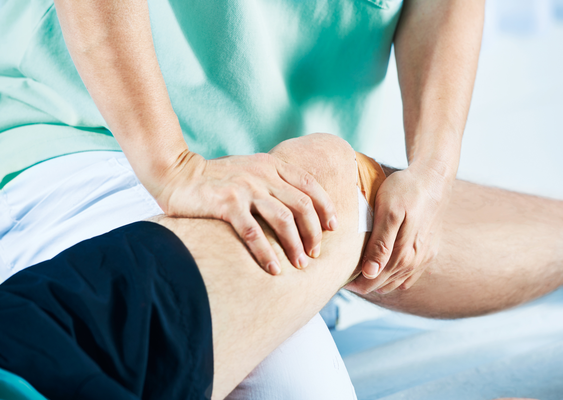 Physiotherapeutin behandelt Knie eines Patienten